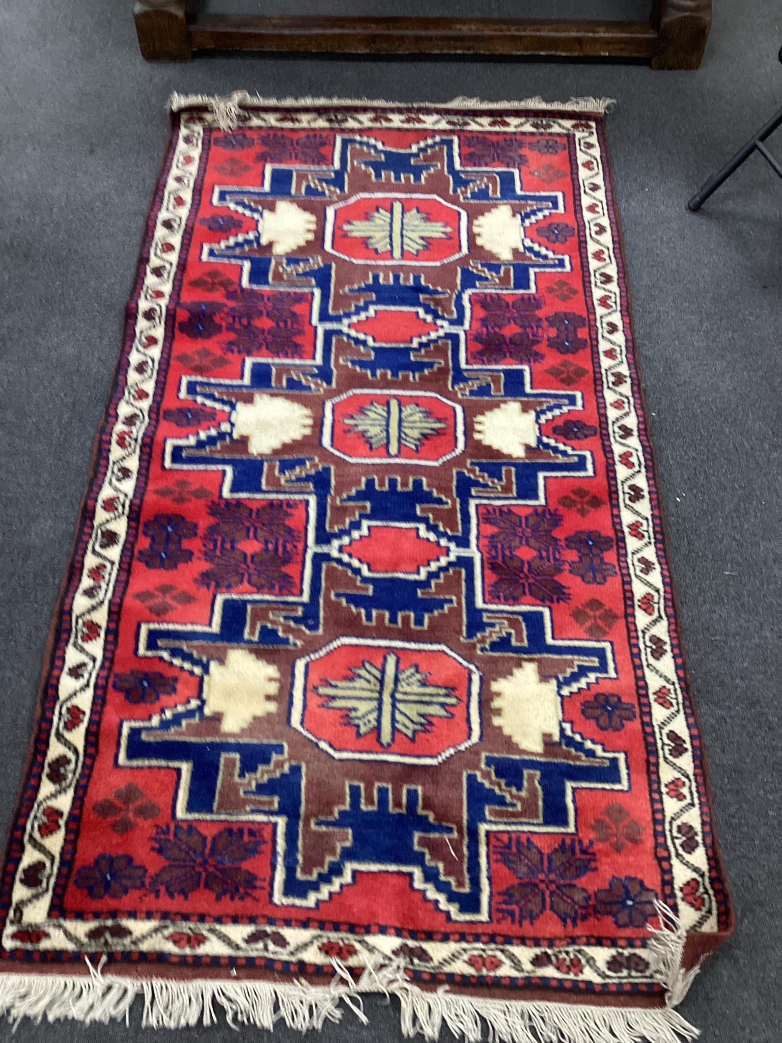 A Caucasian style red ground triple medallion rug, 180 x 98cm